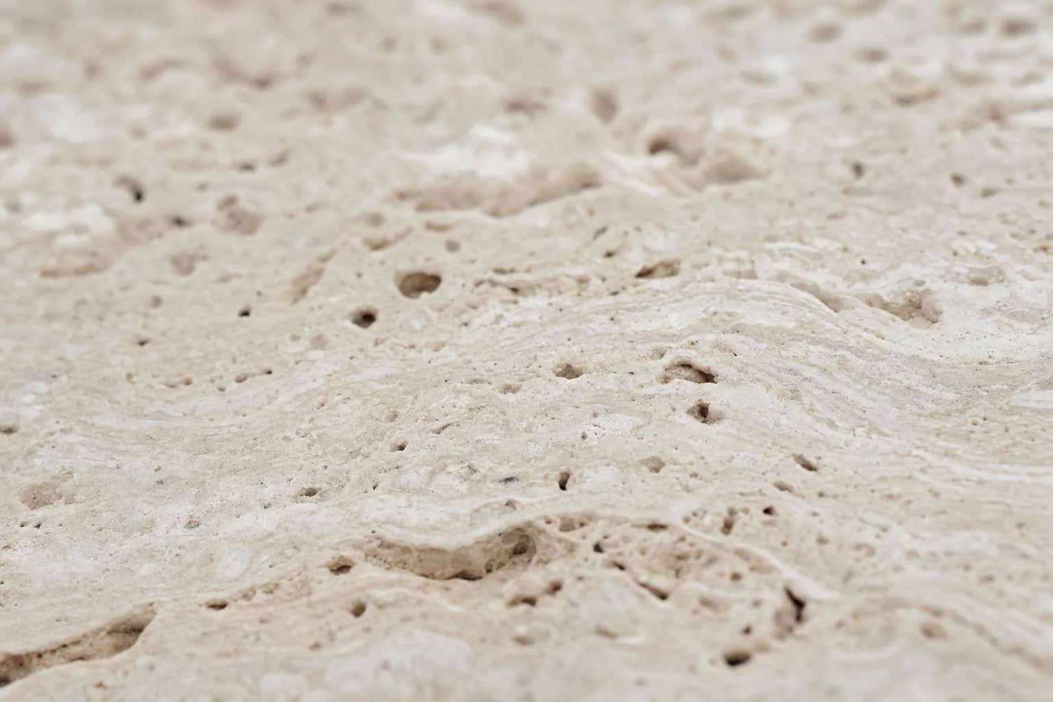 Close detail of a honed travertine paver showing its natural pitting and banding